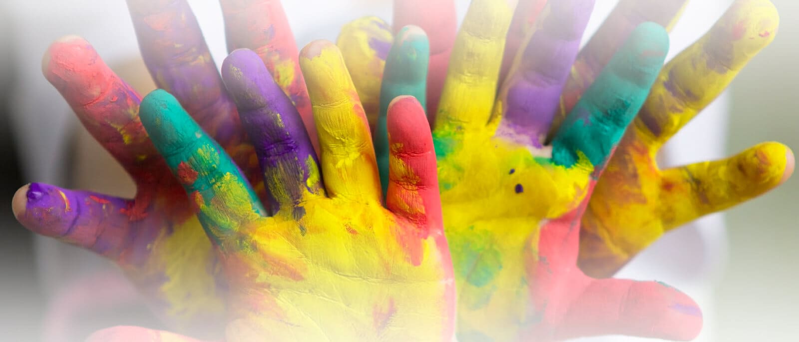 Manos de niños con pinturas de dedos de muchos colores para hacer manualidades