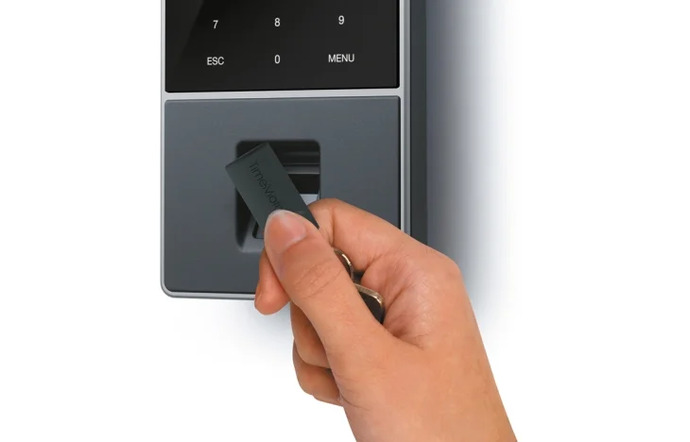 Mano con llavero fichando en reloj para control de presencia TimeMoto