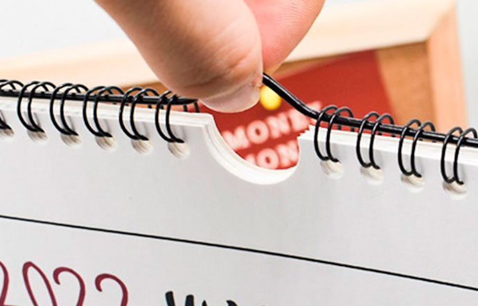 Mano cogiendo calendario encuadernado con wire-O y colgador