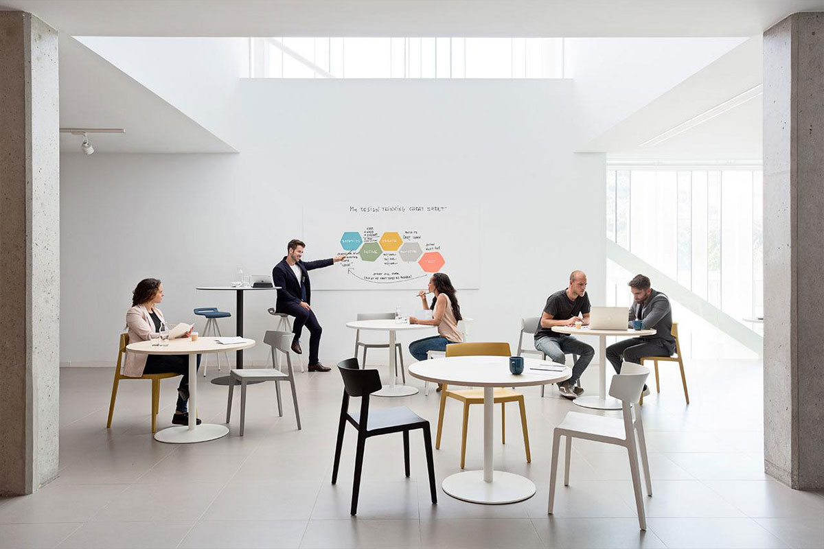 Reunión en sala multidisciplinar con mesas de centro con apoyo central Tabula
