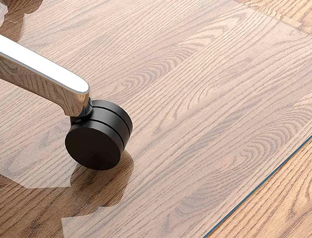Silla de oficina sobre alfombrilla protectora en suelo de madera