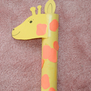 Girafa creada con cuello de canuto de cartón de un rollo de papel de cocina forrado con papel charol amarillo brillante y manchas de cartulina marrón