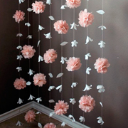 Decoración de pared con flores colgantes realizada con papel seda en rosa y blanco pastel