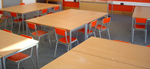 Silla escolar con asiento y respaldo de madera en naranja y estructura metálica de acero
