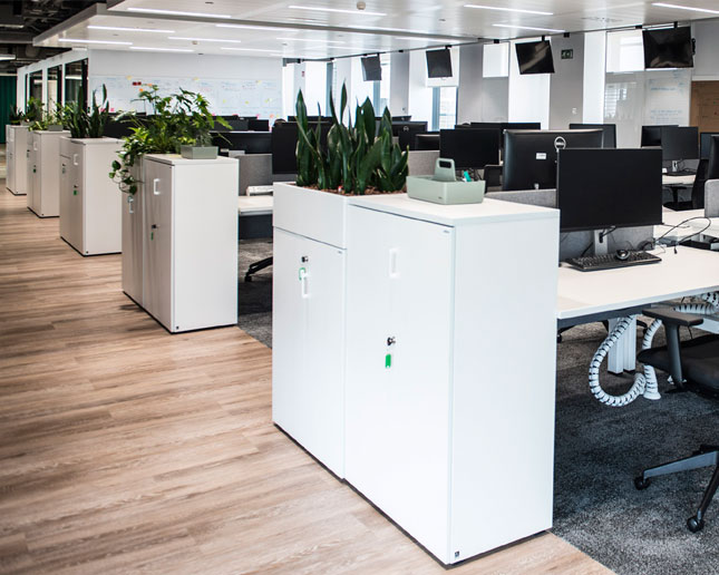 Dos armarios blancos de diferentes alturas con una jardinera encima