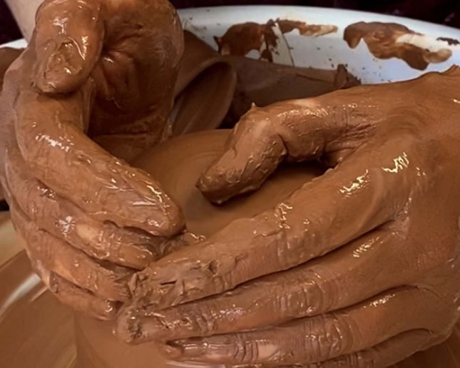 Manos modelando arcilla roja natural Sio-2 en torno