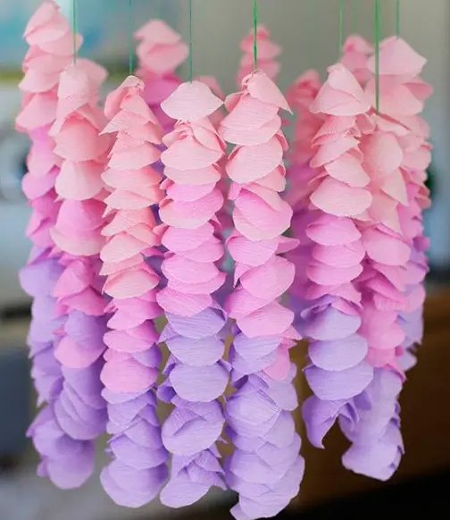 Guirnaldas colgantes en tonos rosas y lilas hechas con papel crepé para decoración de fiestas