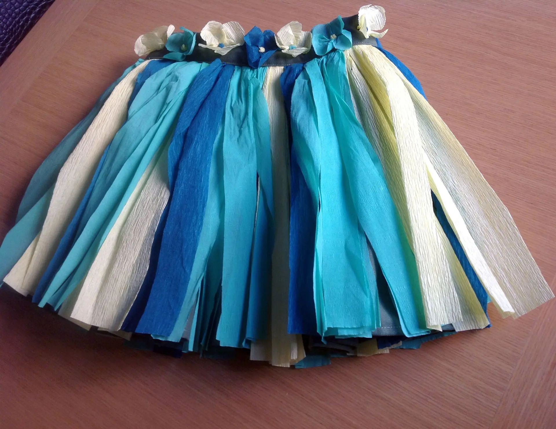 Falda hawaiana infantil fabricada con tiras de papel crespón en tonos azules, verde y amarillo
