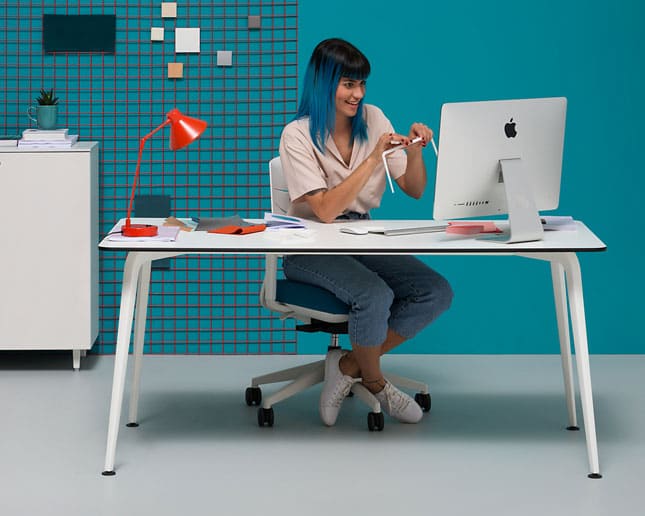 Mujer con pelo azul trabajando en mesa Twist diseño italiano elegante y contemporáneo
