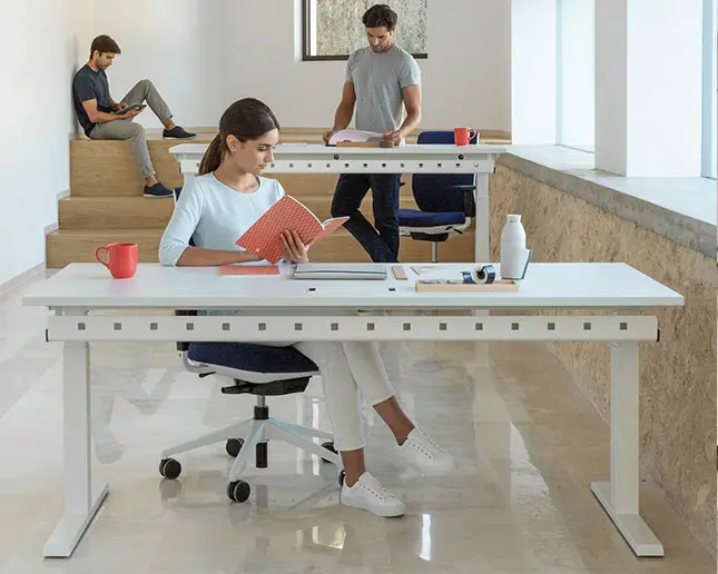 Jóvenes estudiando y trabajando en mesa de oficina Actiu Mobility Step con estructura elevable regulable en altura
