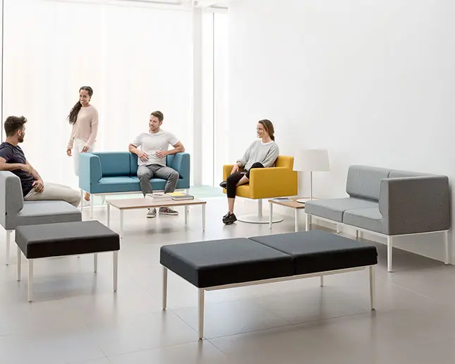 Grupo de personas conversando en sofás modulares Longo Actiu gris y azul en oficina moderna