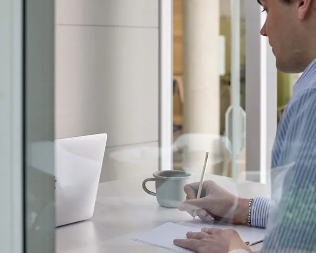 Interior de cabina Qyos con diseño ergonómico y mesa integrada con trabajador escribiendo en ella