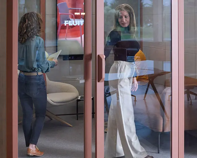 Mujeres cerrando cabina Qyos modular versátil para reuniones y colaboración