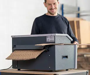 Trabajador reciclando cajas de cartón en esterillas de relleno acolchado para embalaje