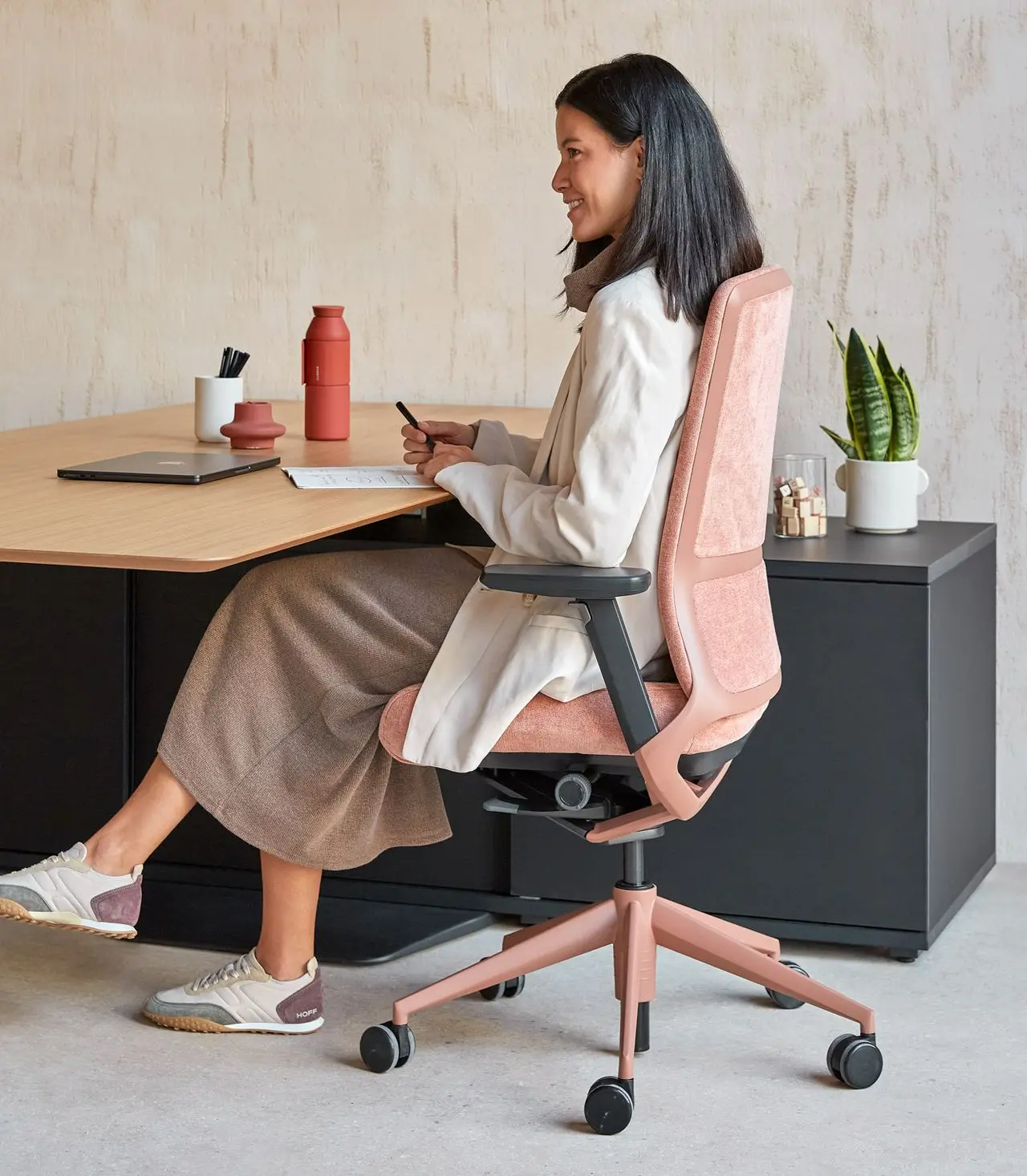 Mujer sentada en despacho con silla TNK 500 de Actiu en cobre y coral