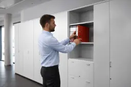 Hombre guardando archivador en armario