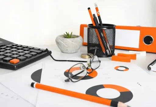 Mesa con calculadora, archivador, gafas, papel, cuaderno y artículos de escritura