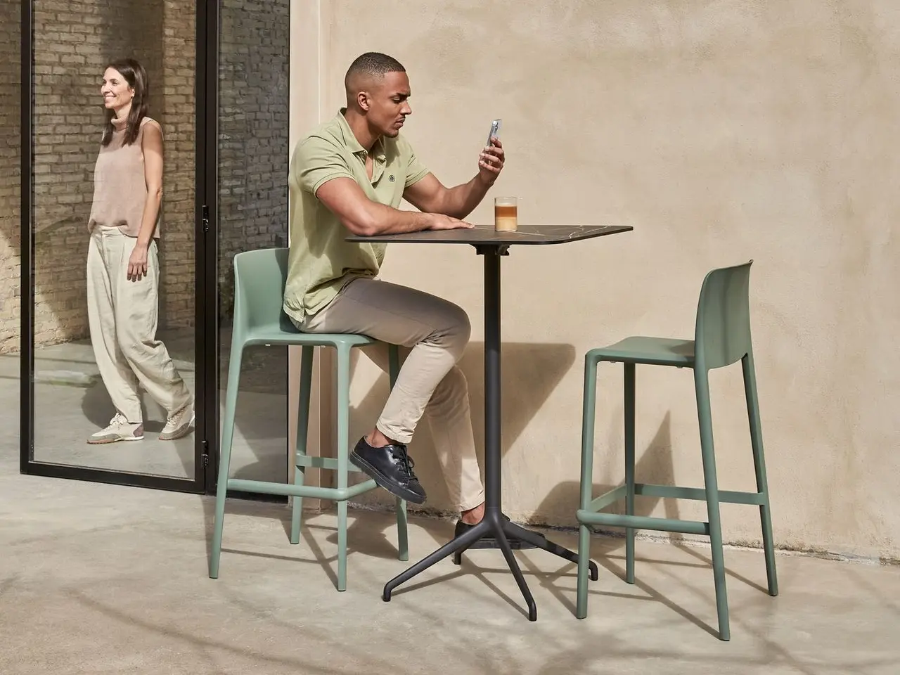 Hombre mirando su móvil en terraza con mesa Tabula TAR 40