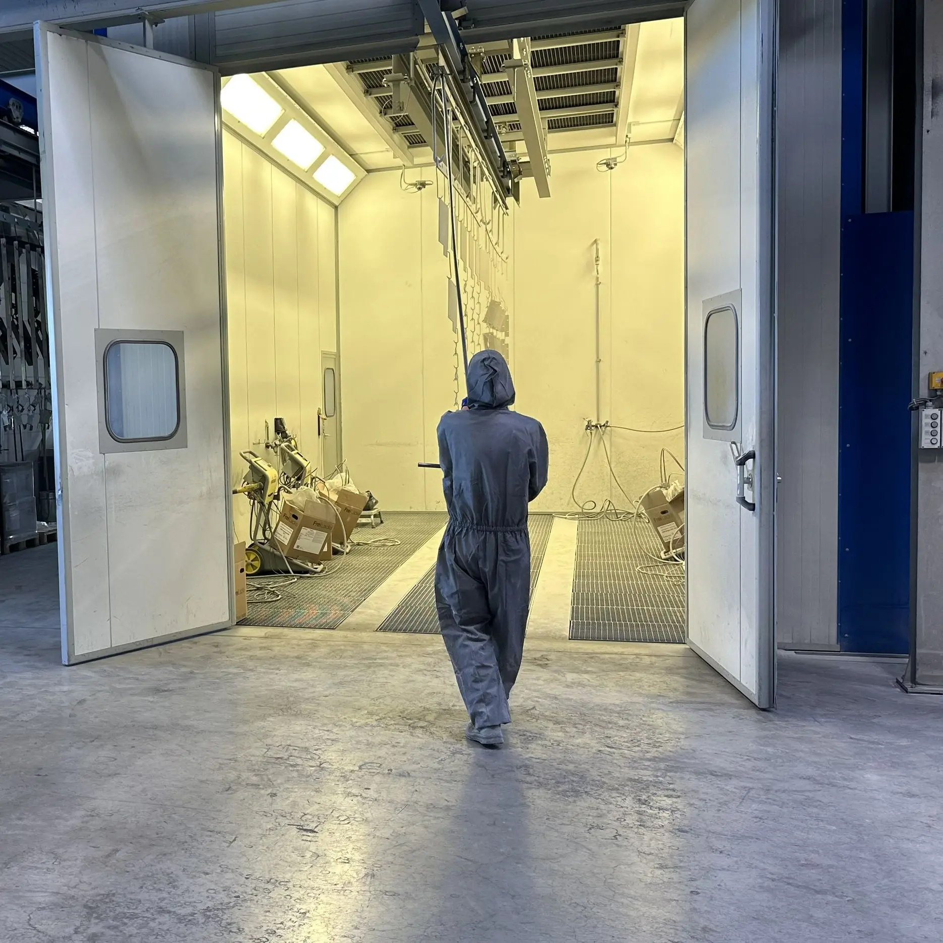Las prensas compatcadoras reacondicionadas se pintan para que, además de su funcionamiento, su imagen sea de una máquina nueva Operario de HSM pintando prensas de segunda mano en cabina de pintura