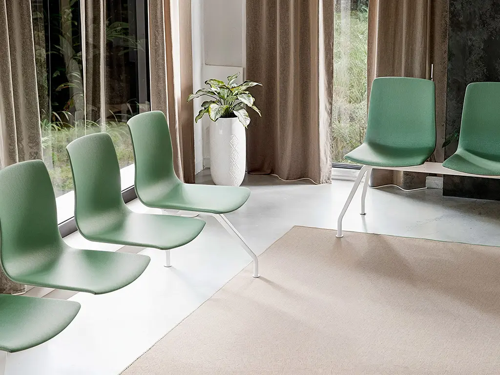Bancadas Noom 50 Actiu en verde en sala de espera con luz natural y planta decorativa