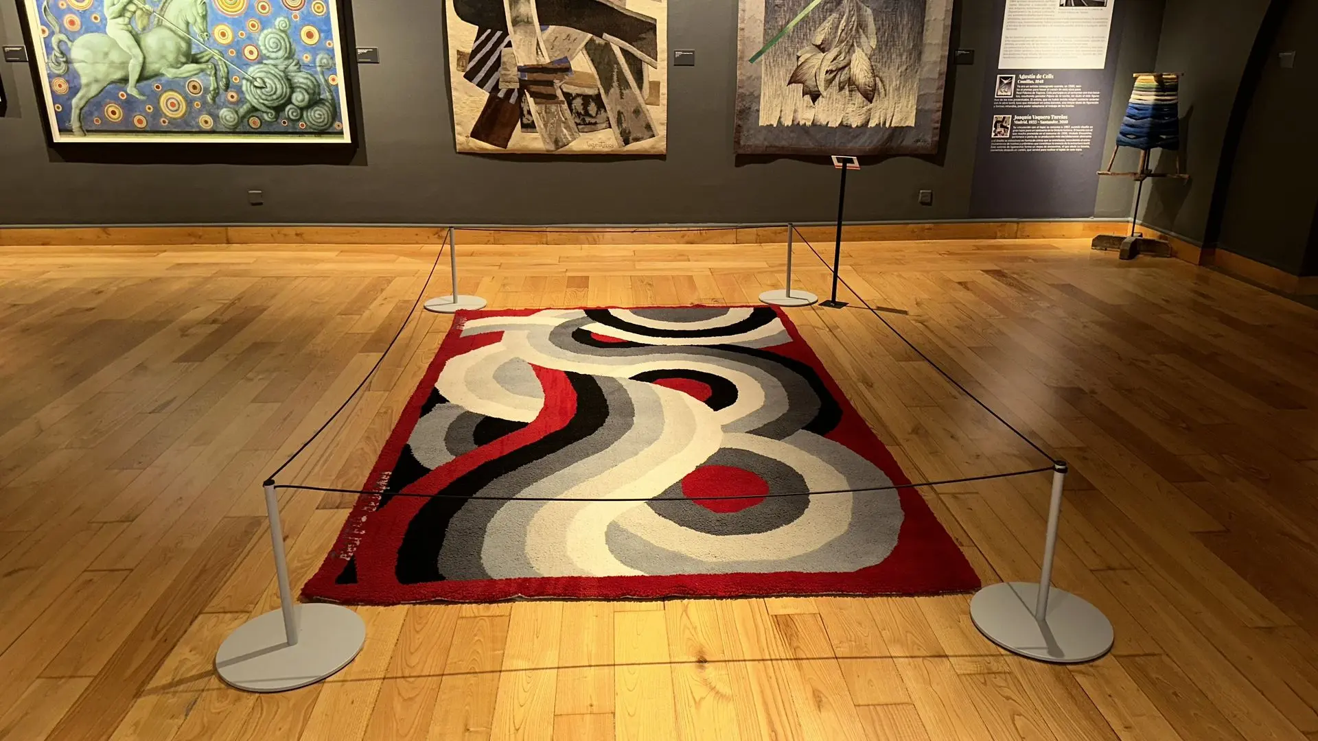 Vista frontal de una alfombra contemporánea roja, negra y gris con un poste Gallery Mini en cada esquina