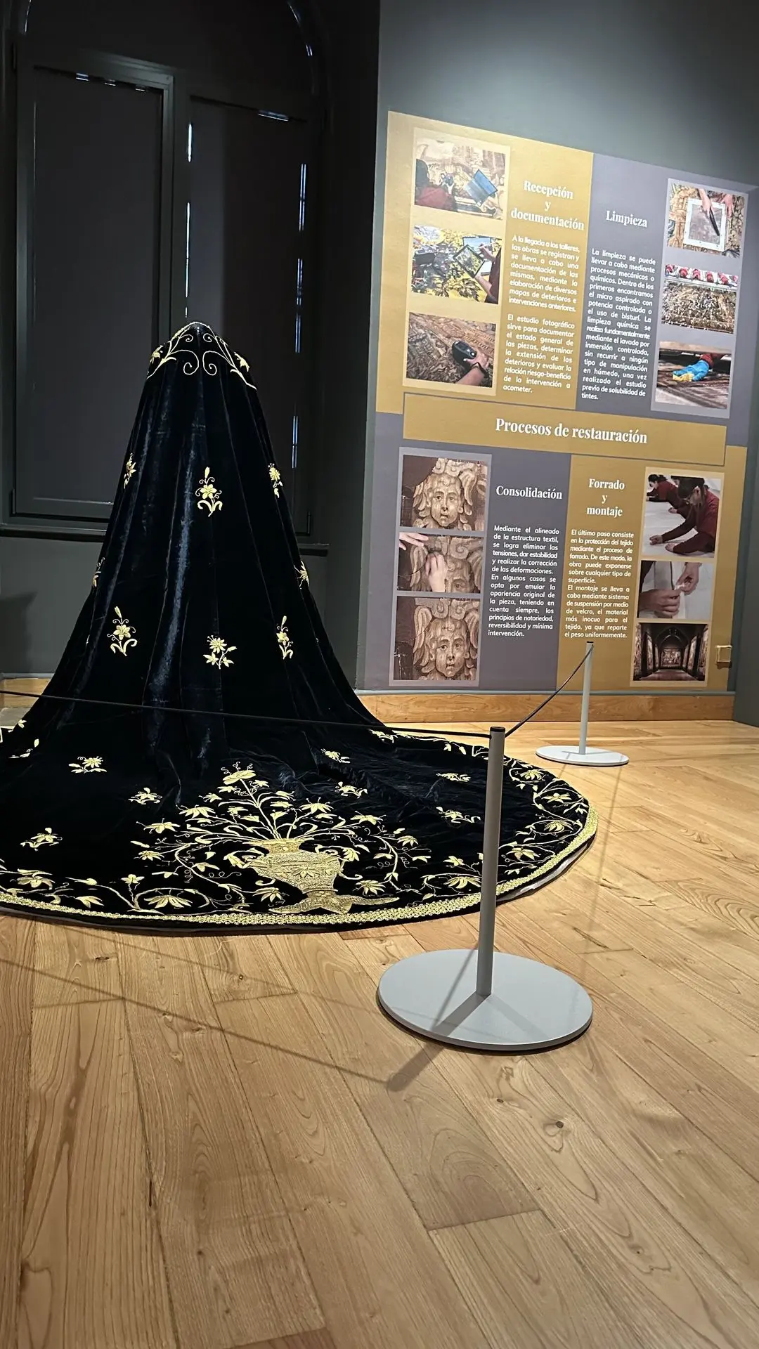 Poste Gallery Mini delante del manto de la Virgen Dolorosa y de los paneles sobre restauración textil