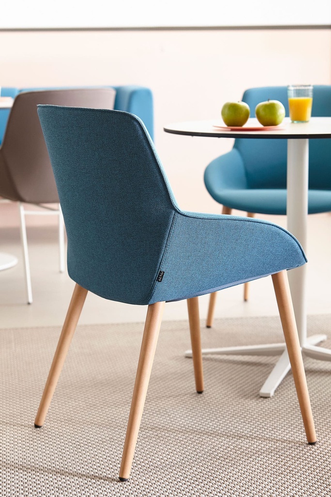 Silla Noom 30 con 4 patas de madera cónicas y tapizado en azul en zona de descanso