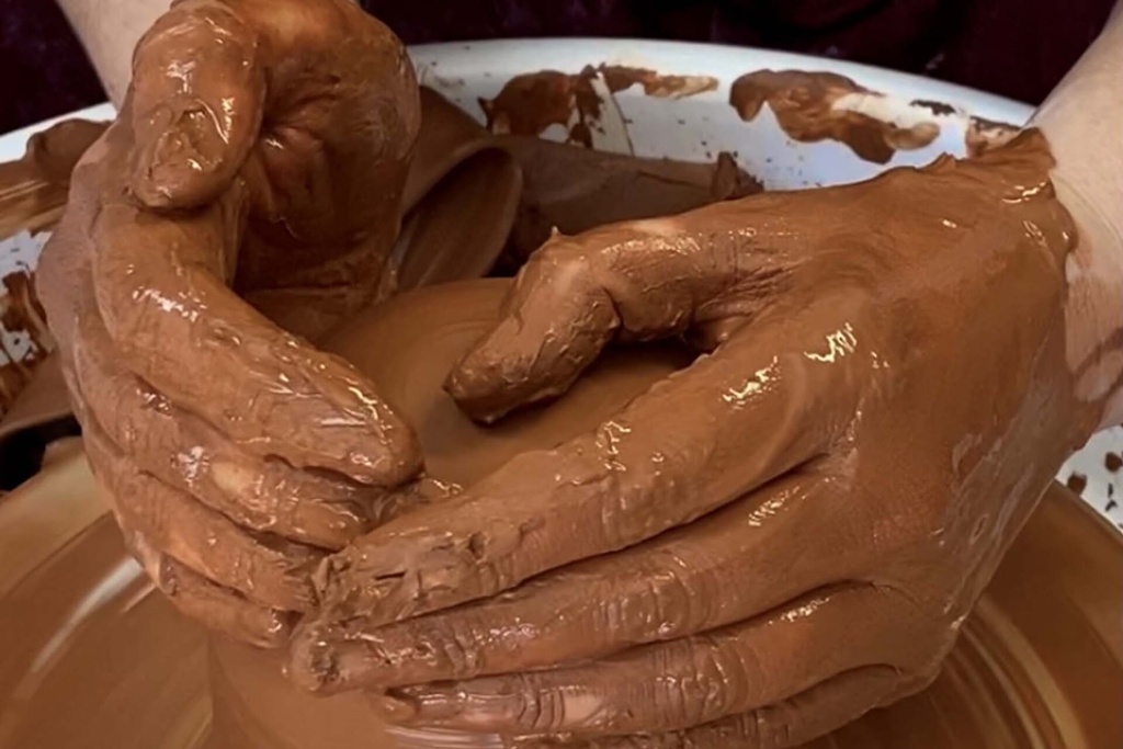 Manos modelando figura con arcilla roja natural Sio-2 sobre torno