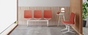 Bancada Urban con estructura blanca y tres asientos en tono coral con fondo de palillería