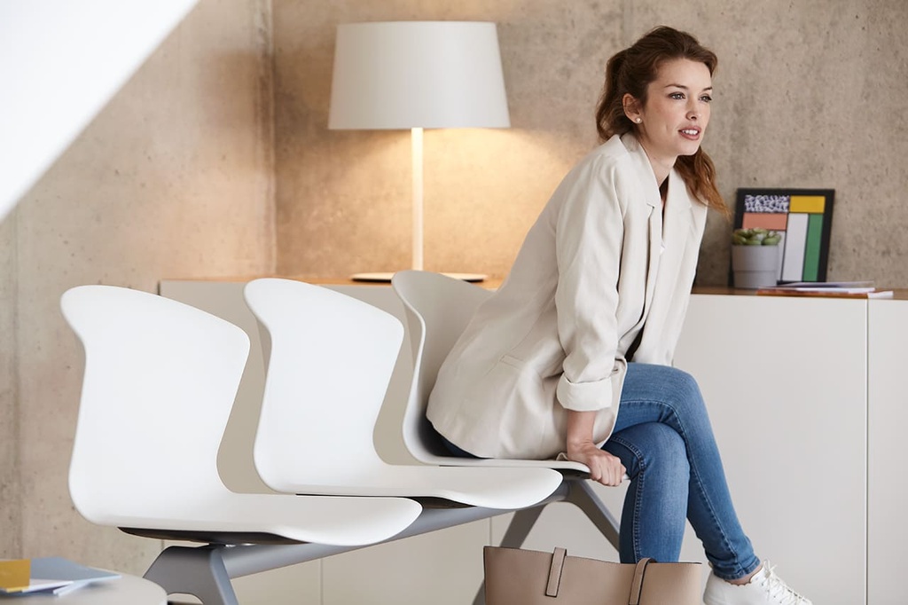 Mujer sentada en bancada Whass blanca en sala de espera de recepción de clientes