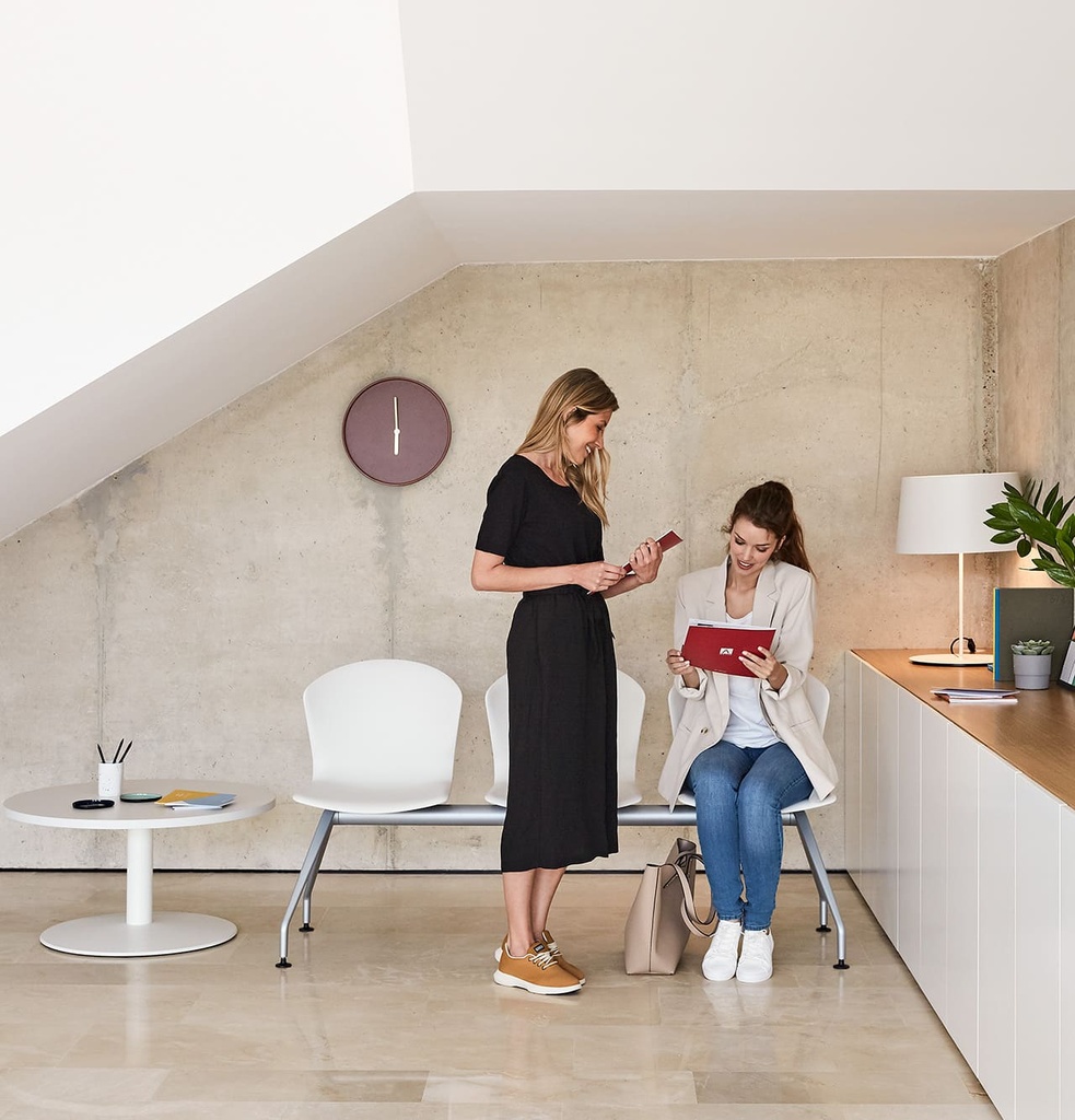 Mujeres conversando en bancada Whass blanca en sala de espera de recepción bajo escalera