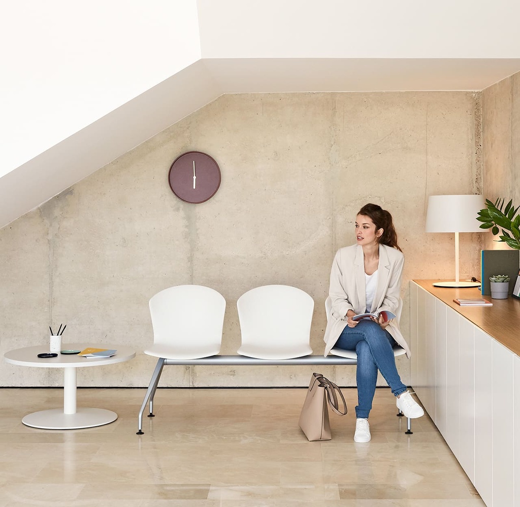 Mujer sentada en bancada Whass blanca en sala de espera de recepción moderna